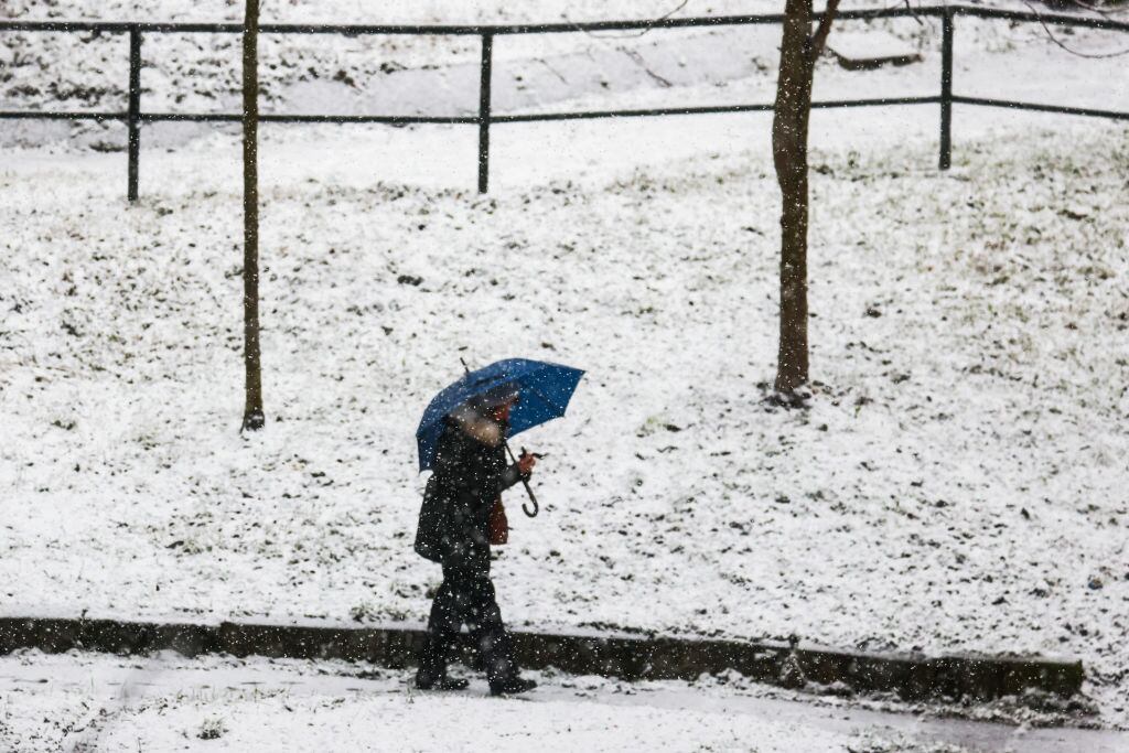 Un hombre se resguarda de la nieve ocn un paragüas.