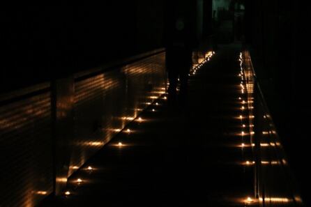 Un vecino cruza por el puente iluminado con velas