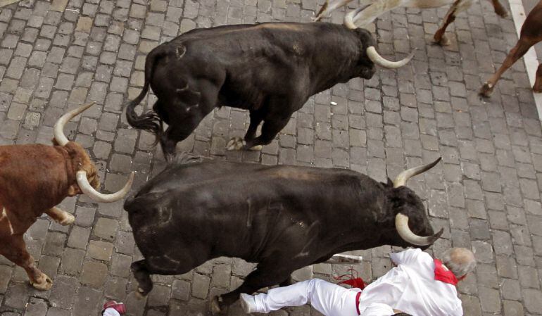 Un grupo de mozos caen ante tres toros de la ganadería extremeña de Jandilla en la entrada a la Plaza Consistorial de Pamplona durante el quinto encierro de los Sanfermines 2016.