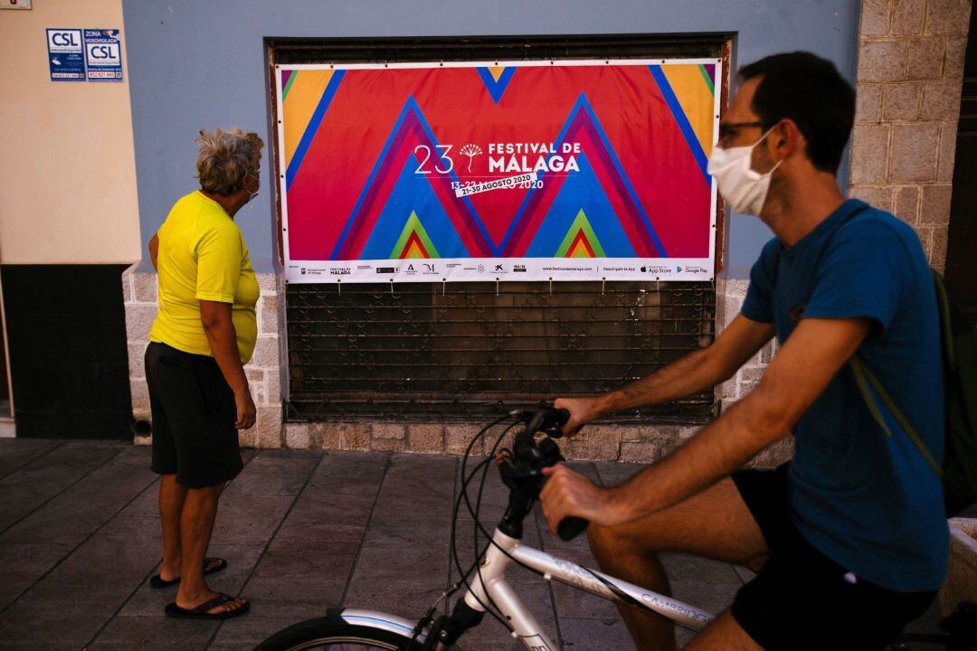 Una persona observa uno de los carteles publicitarios que anuncian el vigésimo tercer Festival de Cine en Español en el centro de Málaga, que se inaugurará mañana viernes después de ser aplazado en marzo por coronavirus y que acapara todas las miradas de la industria cinematográfica al convertirse en el primer gran encuentro del sector tras el confinamiento