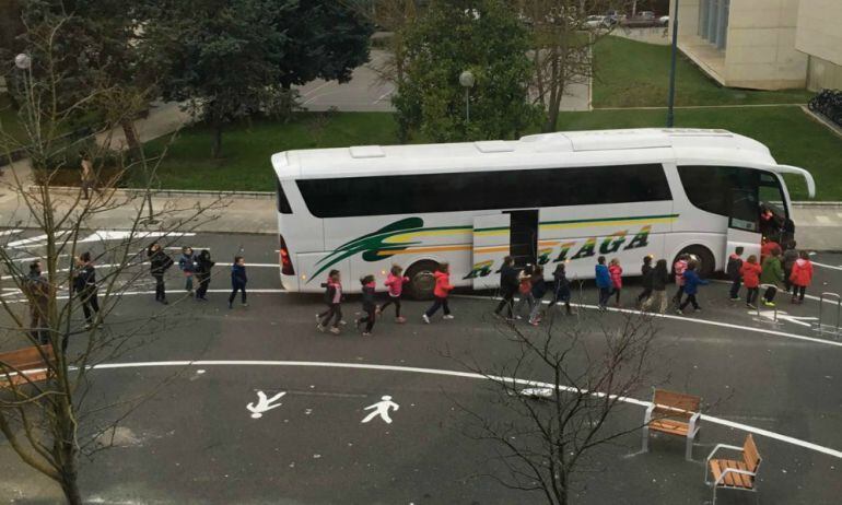 Un grupo de niños y niñas cruza la calzada para ir al autobús