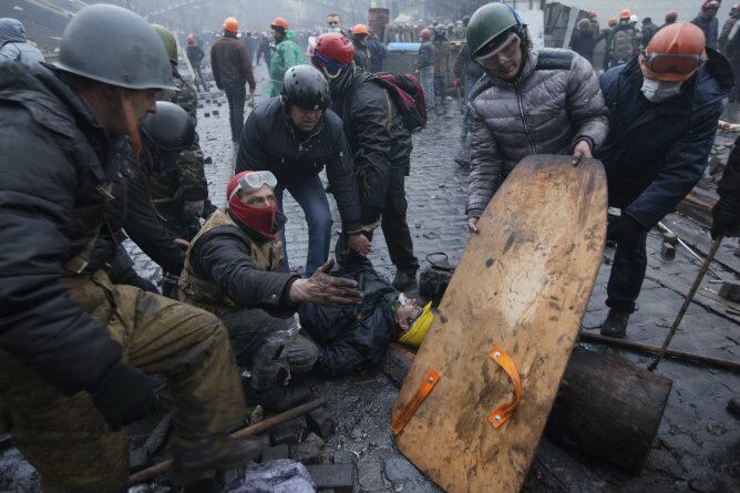 Activistas de la oposición asisten a un manifestante herido durante los enfrentamientos con la policía en la Plaza de la Independencia en Kiev