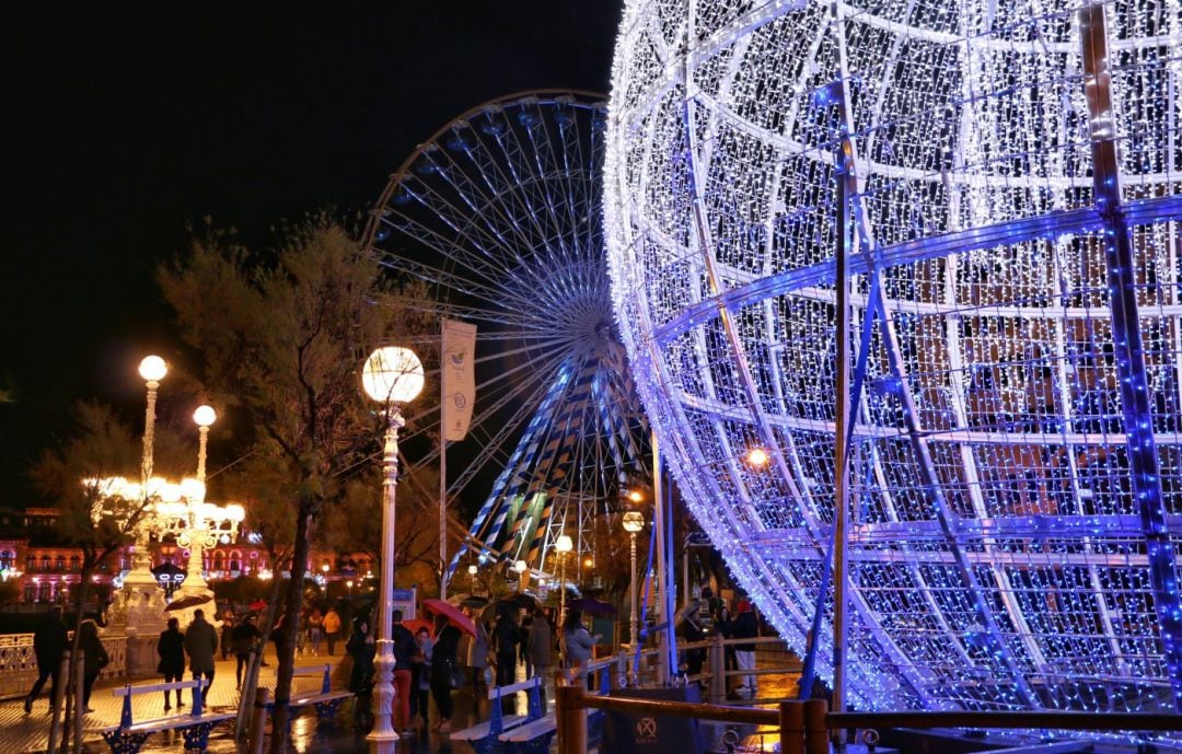 Vista de dos de los principales atractivos de la Navidad en San Sebastián, en primer plano la gran bola, y en segundo la noria instalada en Alderdi Eder.