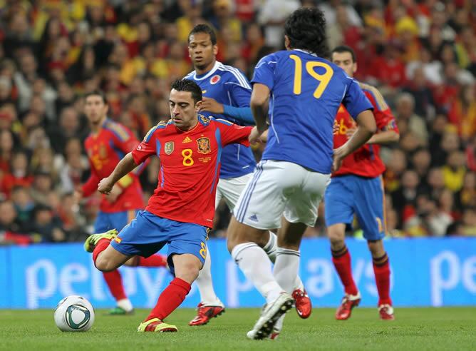 El centrocampista de la selección española de fútbol Xavi Hernández, con el balón ante los jugadores de la selección colombiana