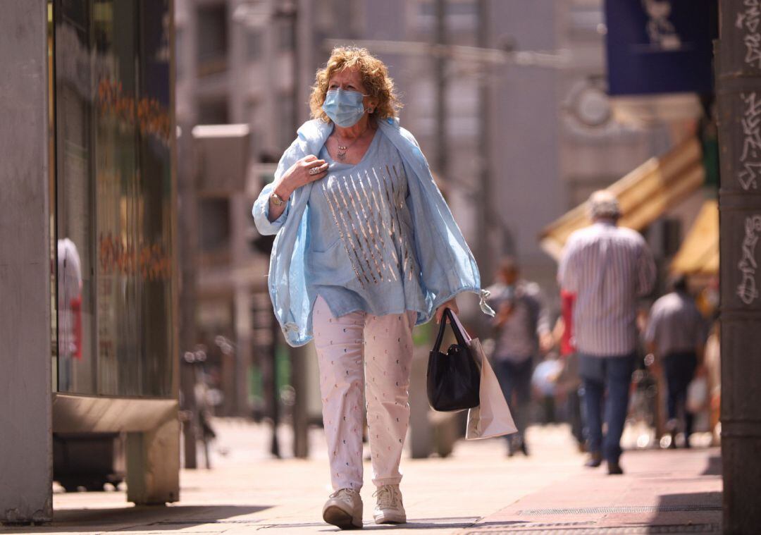 Una mujer pasea con mascarilla.