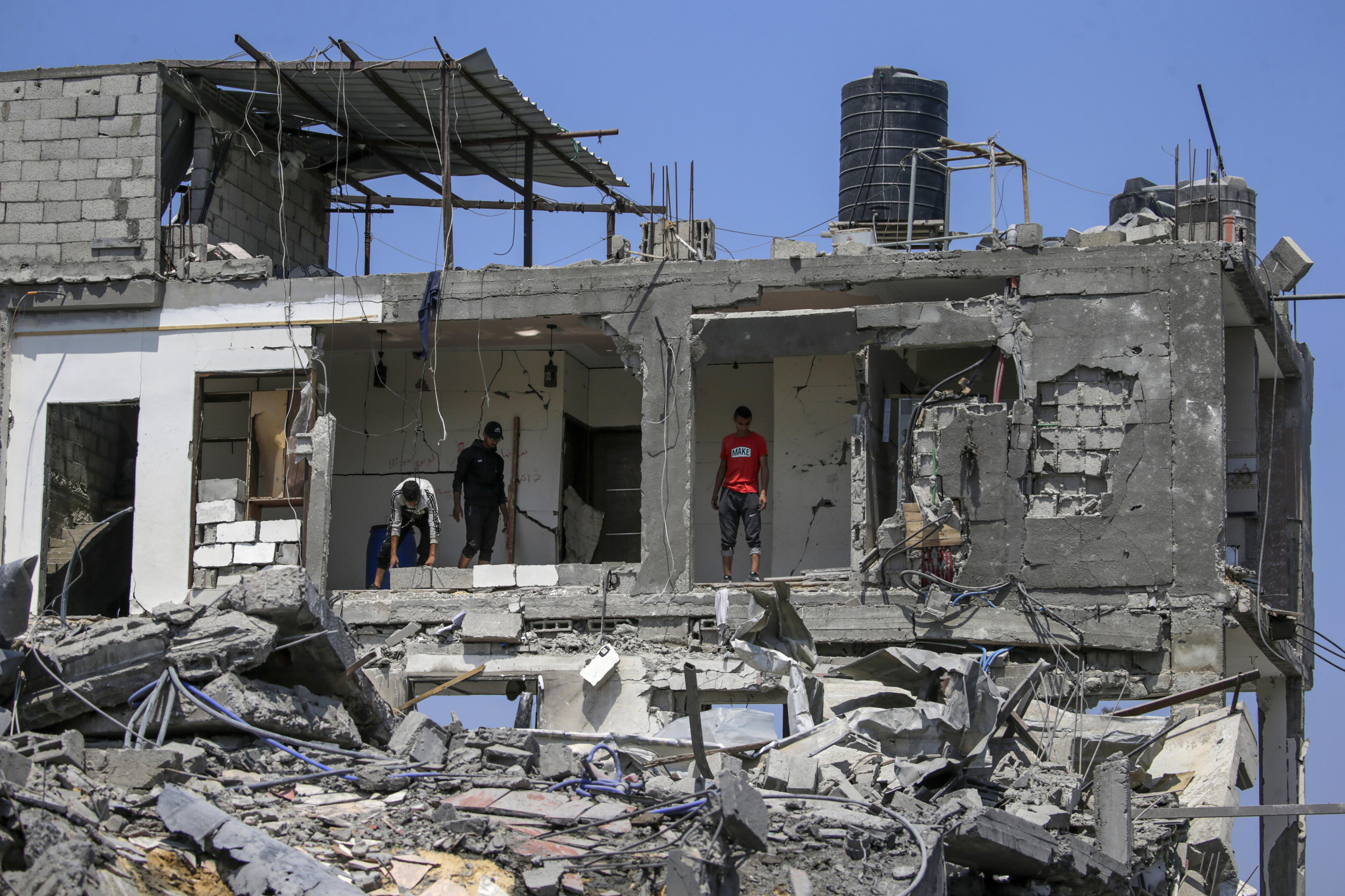 Varios palestinos inspeccionan sus casas destruidas en el campo de refugiados de Al Maghazi. EFE/MOHAMMED SABER