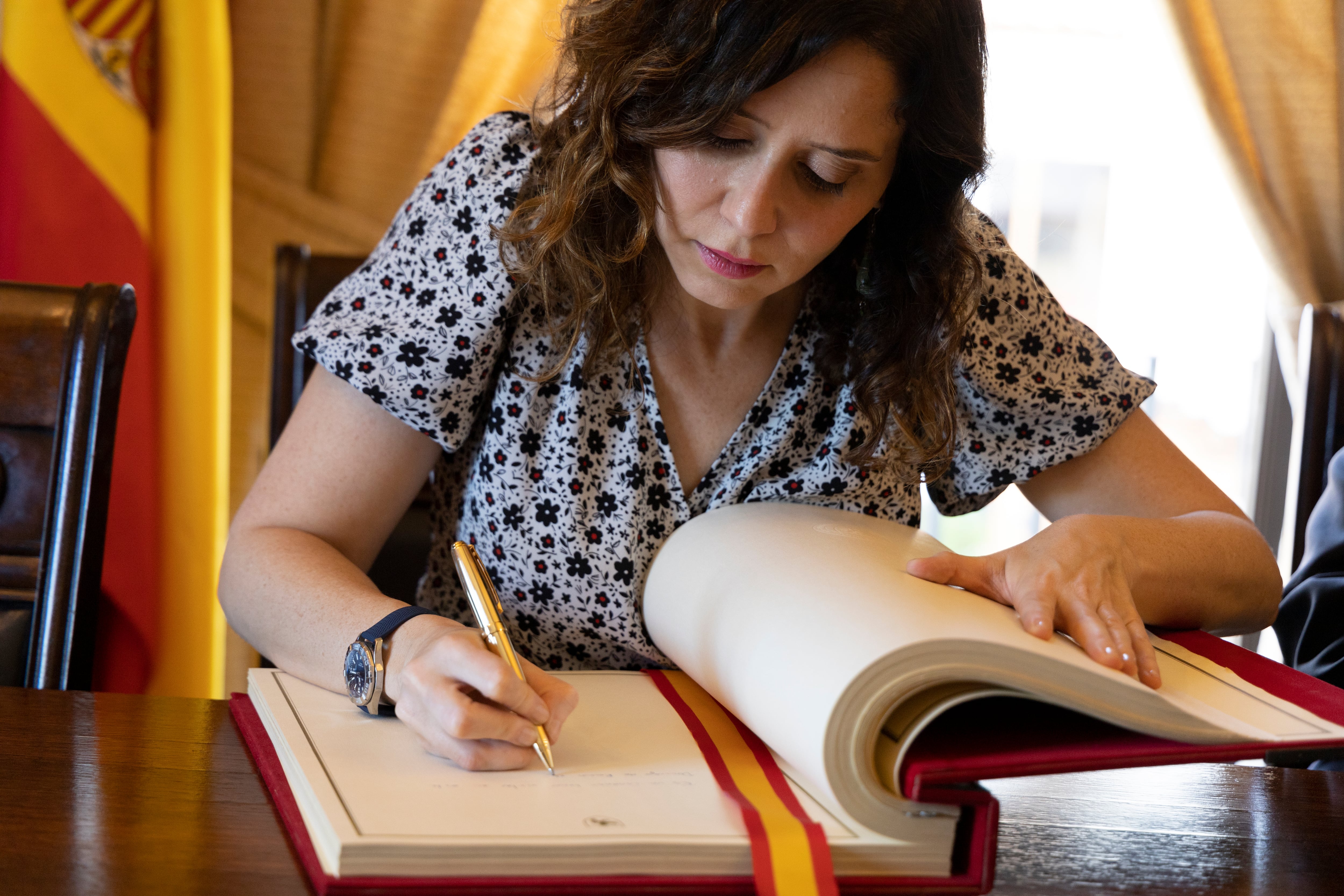 La presidenta de la Comunidad de Madrid, Isabel Díaz Ayuso, firma el libro de invitados durante un evento en Santiago (Chile)