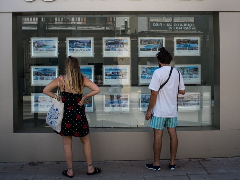 Archivo - Dos personas observan inmuebles en alquiler y en venta en un escaparate de una inmobiliaria ubicada en Palma.