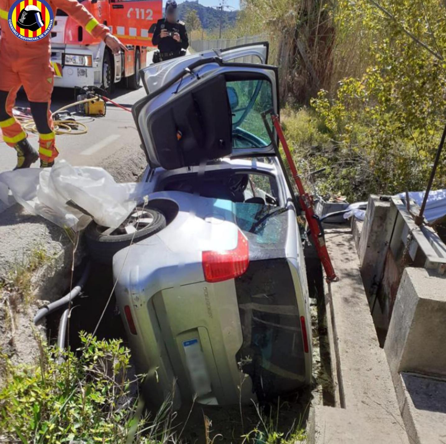 Bomberos junto al vehículo siniestrado en una acequia de Gandia.