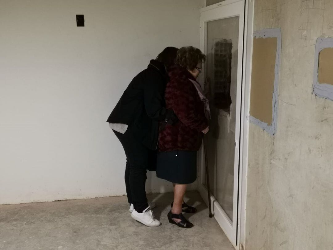 Mercedes Abril y su hija observan a través de un cristal las cajas con los restos humanos donde podría estar su padre y abuelo, ejecutado en 1936.