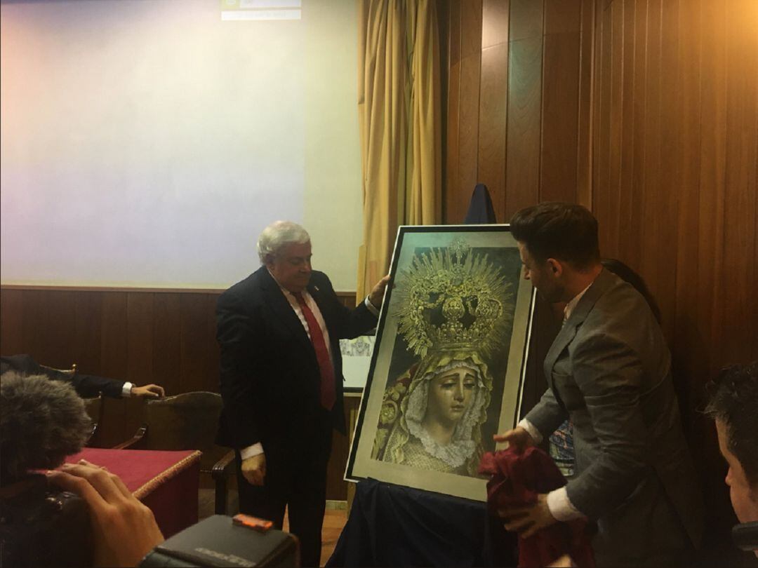 El hermano mayor de Las Cigarreras, Claudio Espejo, y el artista Jonathan Sánchez Aguilera descubren el cartel de la coronación canónica de la Virgen de La Victoria