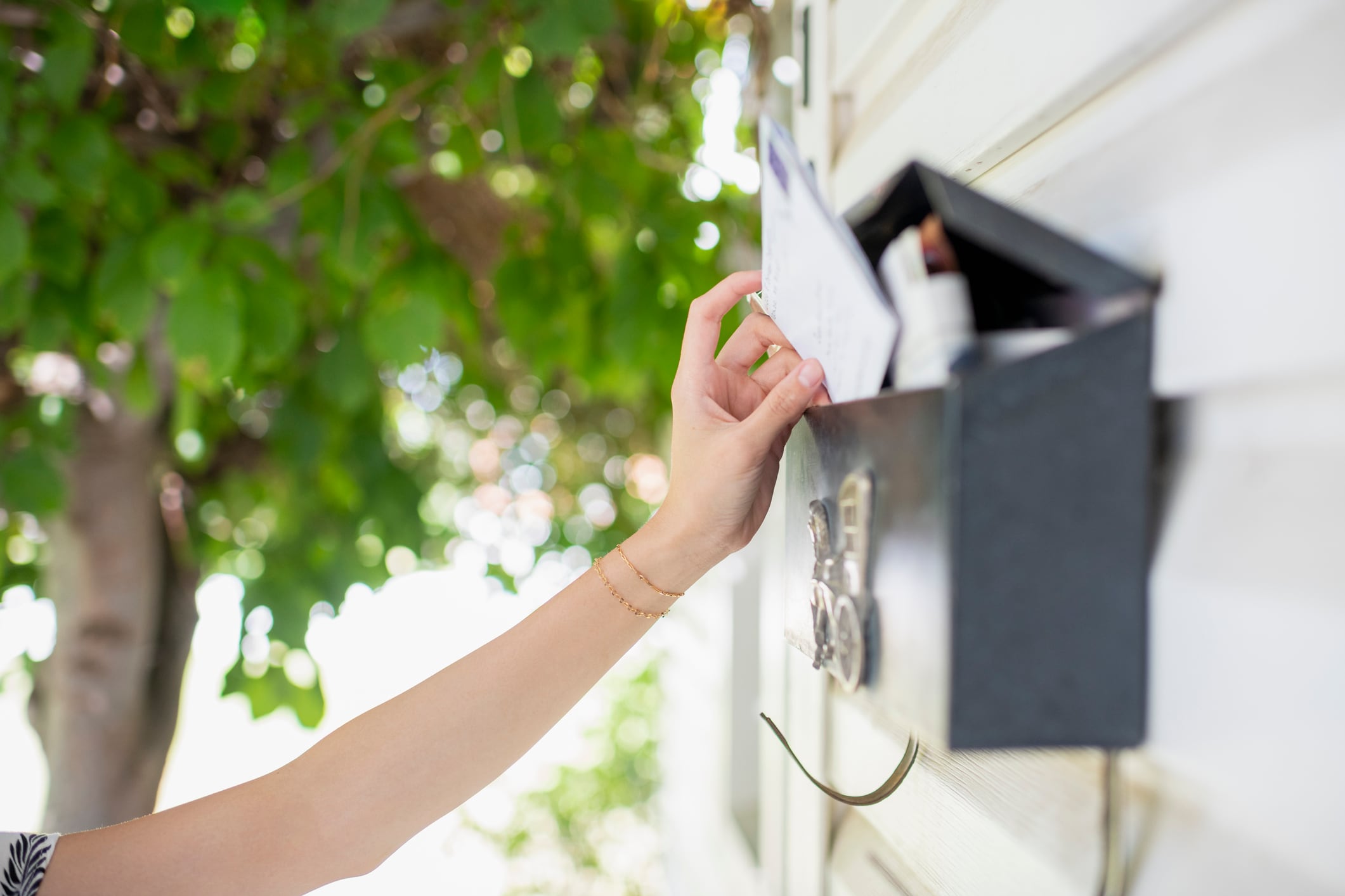 Una mujer recoge una carta del buzón.