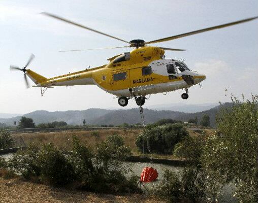 Un helicóptero de los bomberos  llena la cubeta con agua durante un incendio forestal en Macastre, cerca de Valencia.