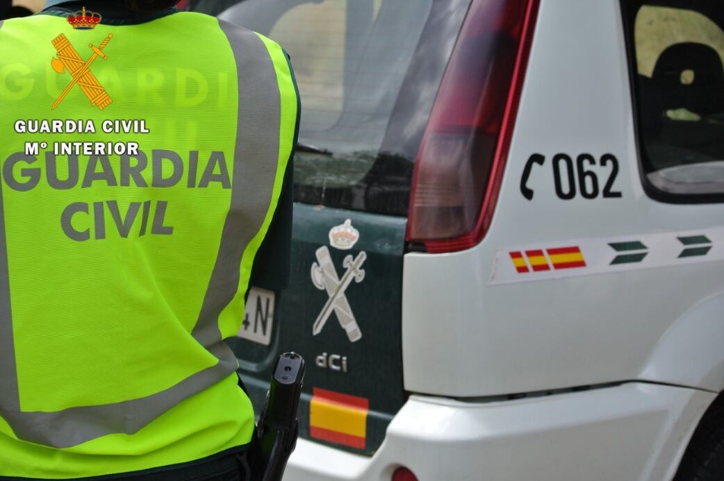 Un guardia civil junto a su coche patrulla.