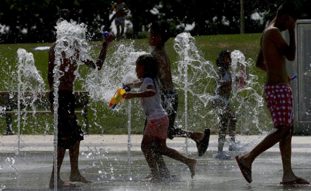 Niños refrescándose en una fuente pública