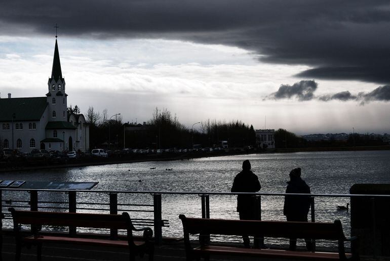 Dos personas caminan ante la sede del Parlamento islandés en Reikiavik, en el día en que Sigmundur Gunnlauggson, dimitió como Primer Ministro.