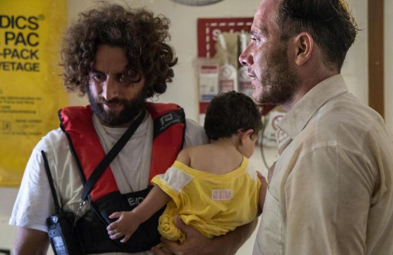 Fotografía de uno de los voluntarios en el operativo de rescate, junto con Azeel y su padre Mohammed, dos de los supervivientes en el naufragio.
