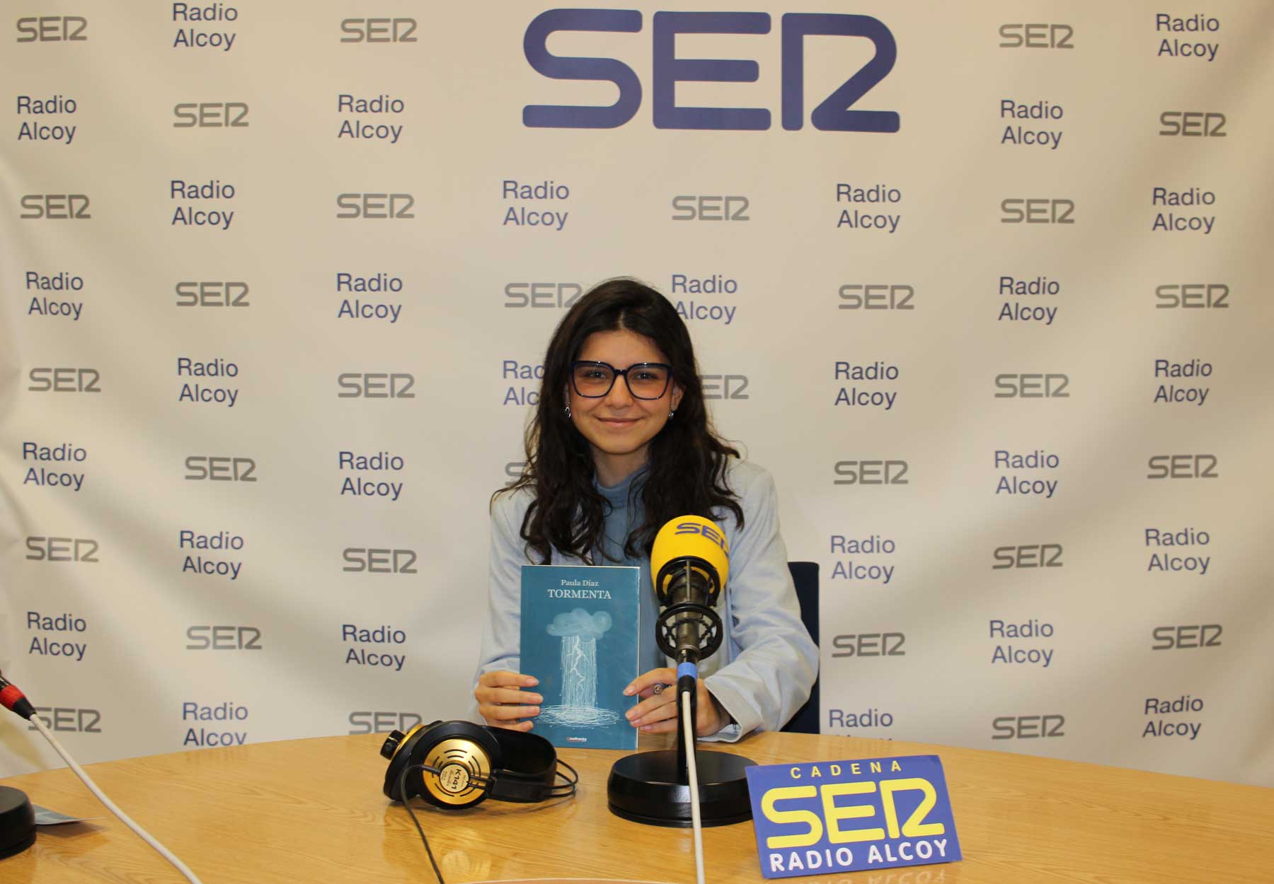 La joven Paula Díaz con un ejemplar del libro &#039;Tormenta&#039; en el estudio central de Radio Alcoy