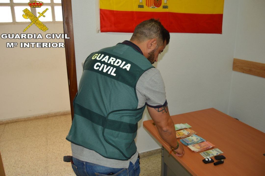 Agente de la Guardia Civil con el dinero decomisado al detenido. 