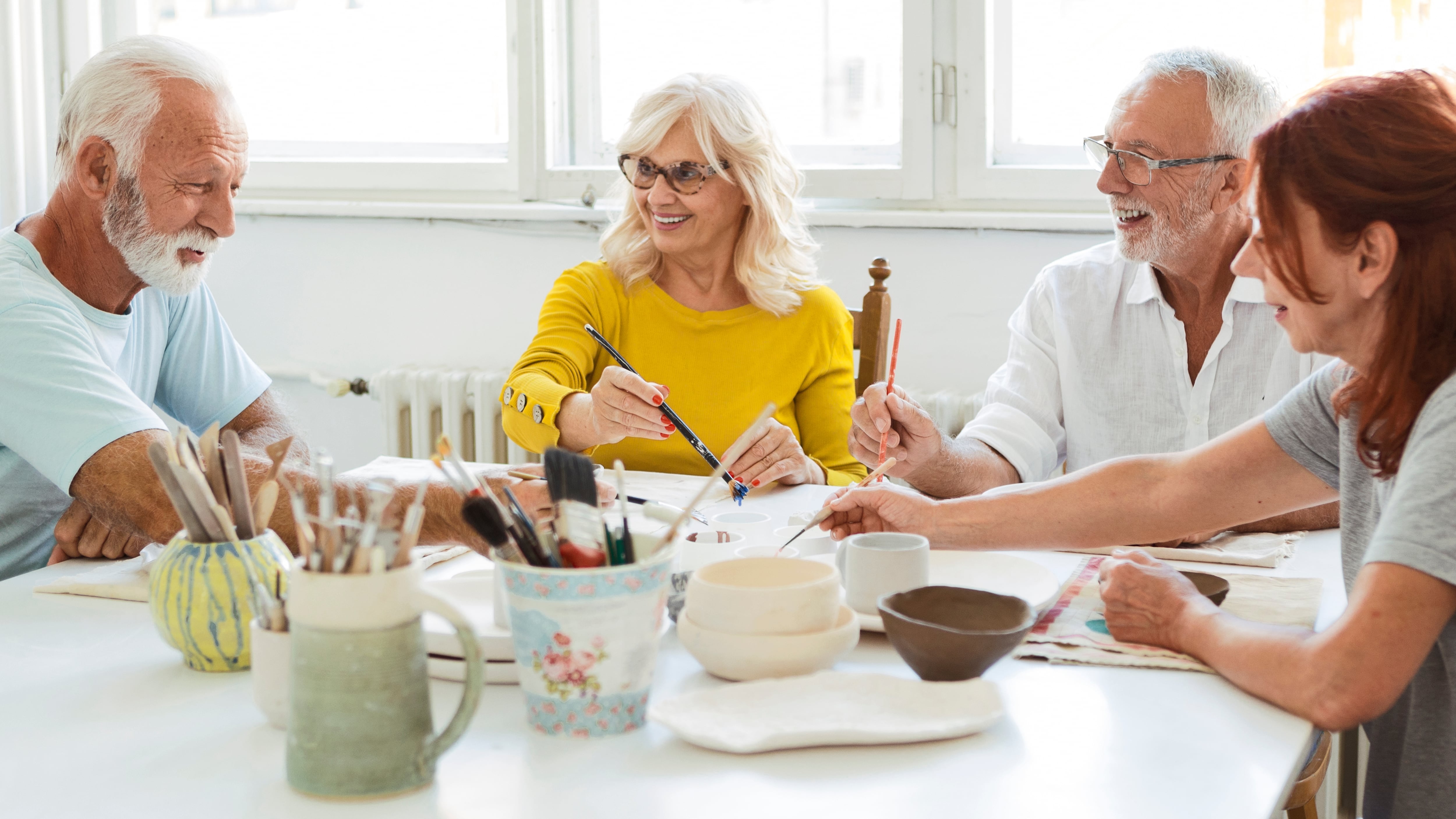 Personas mayores pintan en un taller de cerámica.