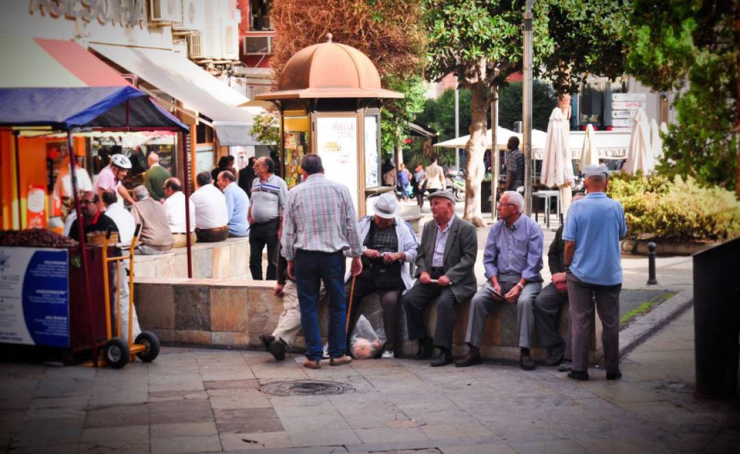 Varias personas sentadas en la confluencia de la plaza de la Constitución con la calle San Clemente de la capital.