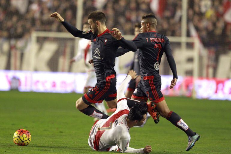 El defensa del Celta de Vigo David Goldar (i) intenta escaparse del delantero venezolano Miku (abajo), del Rayo Vallecano, durante el partido de la vigésimo primera jornada de Liga en Primera División jugado en el estadio de Vallecas, en Madrid.