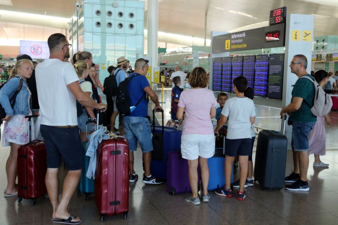 Passatgers mirant les pantalles informatives al Prat