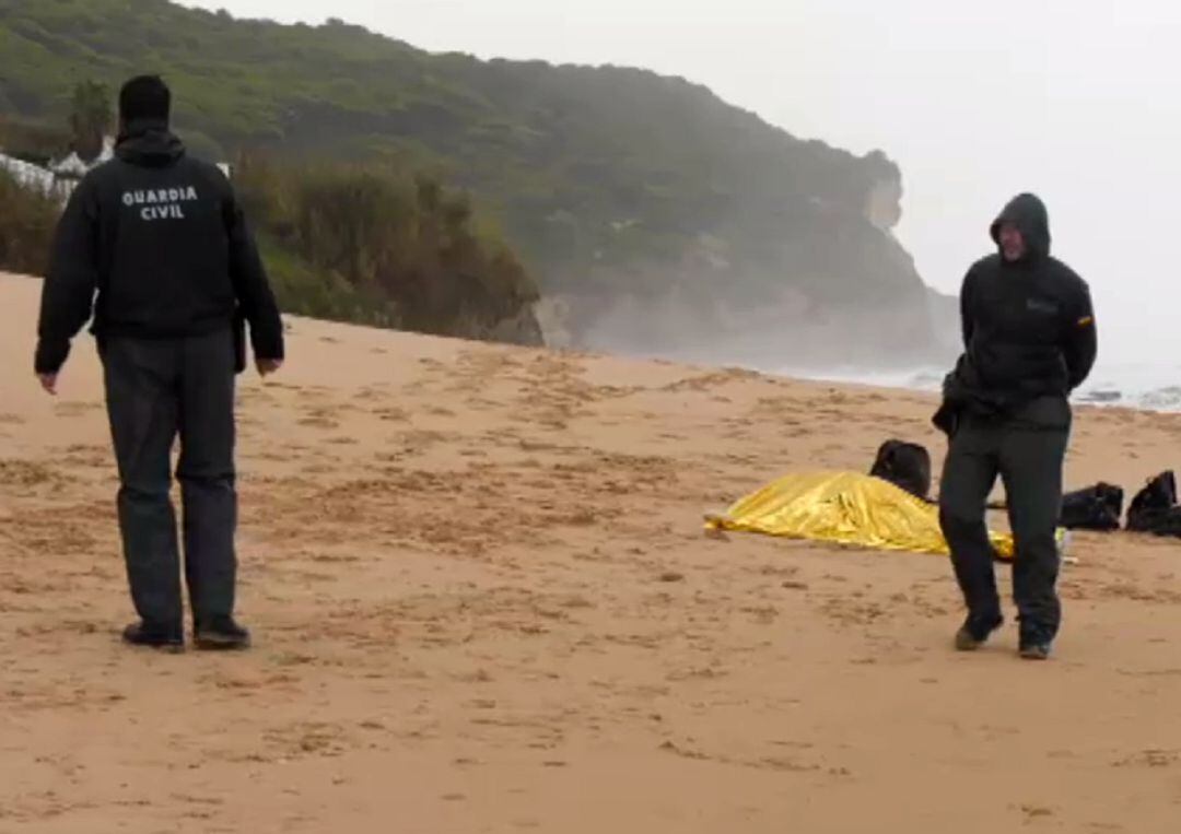 Agentes de la Guardia Civil junto a uno de los cadáveres recuperados en la playa