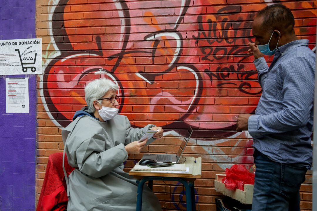 Voluntarios de la Asociación de Vecinos Parque Aluche, en el reparto de cajas de alimentos y producto. En Aluche, Madrid, (España), a 16 de mayo de 2020.