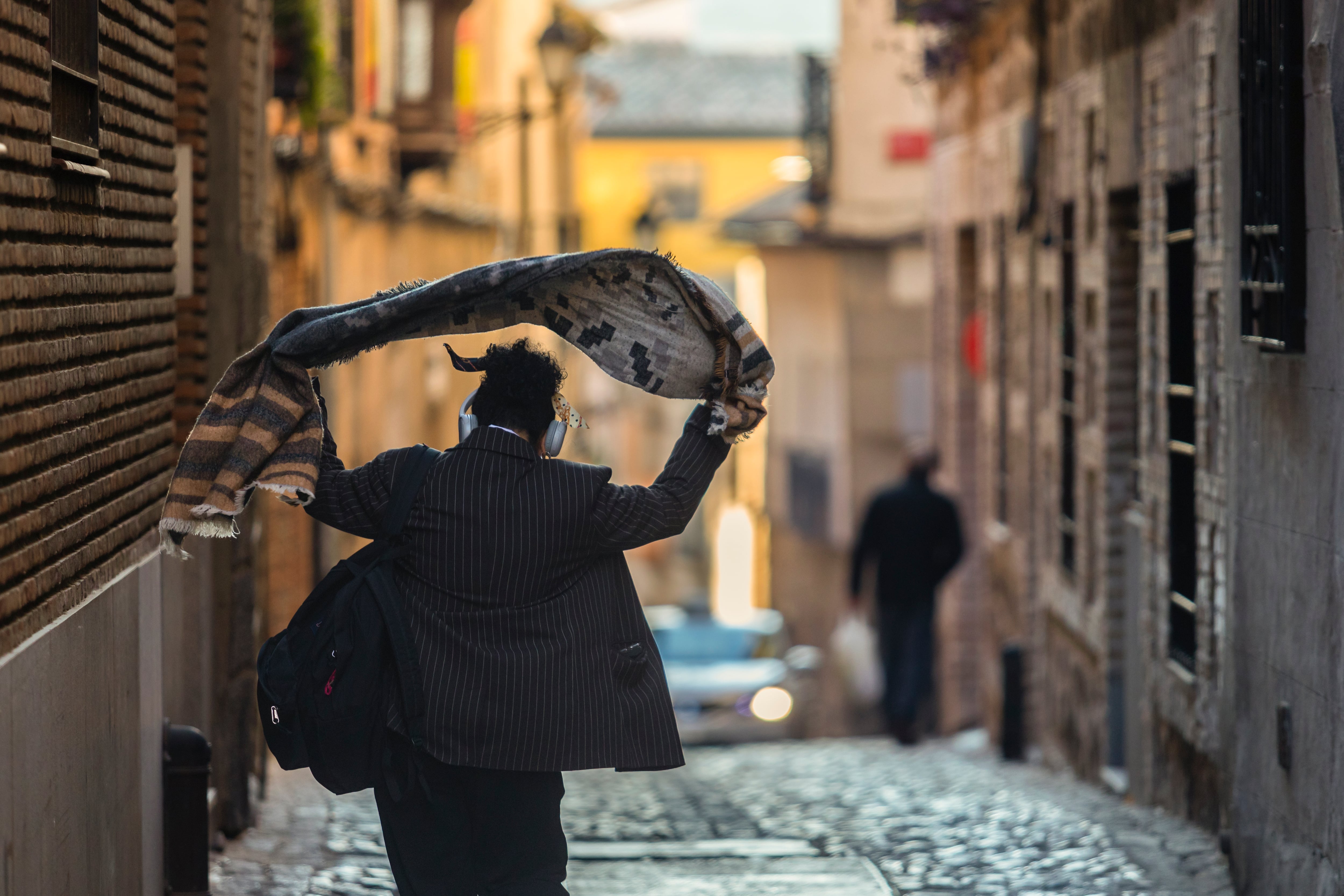 TOLEDO, 30/01/2023.- Una persona se echa una prenda de abrigo sobre los hombros mientras camina por una calle de Toledo este lunes. 