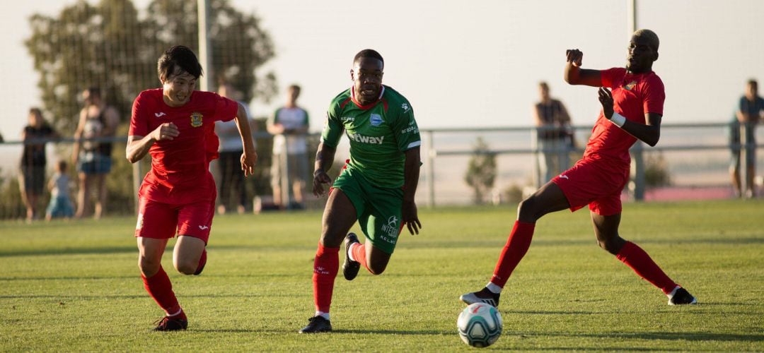 Los fuenlabreños Kato (i) y Souley (d) intentan impedir el avance del jugador vitoriano Twumasi, en el amistoso de este jueves en Los Ángeles de San Rafael.