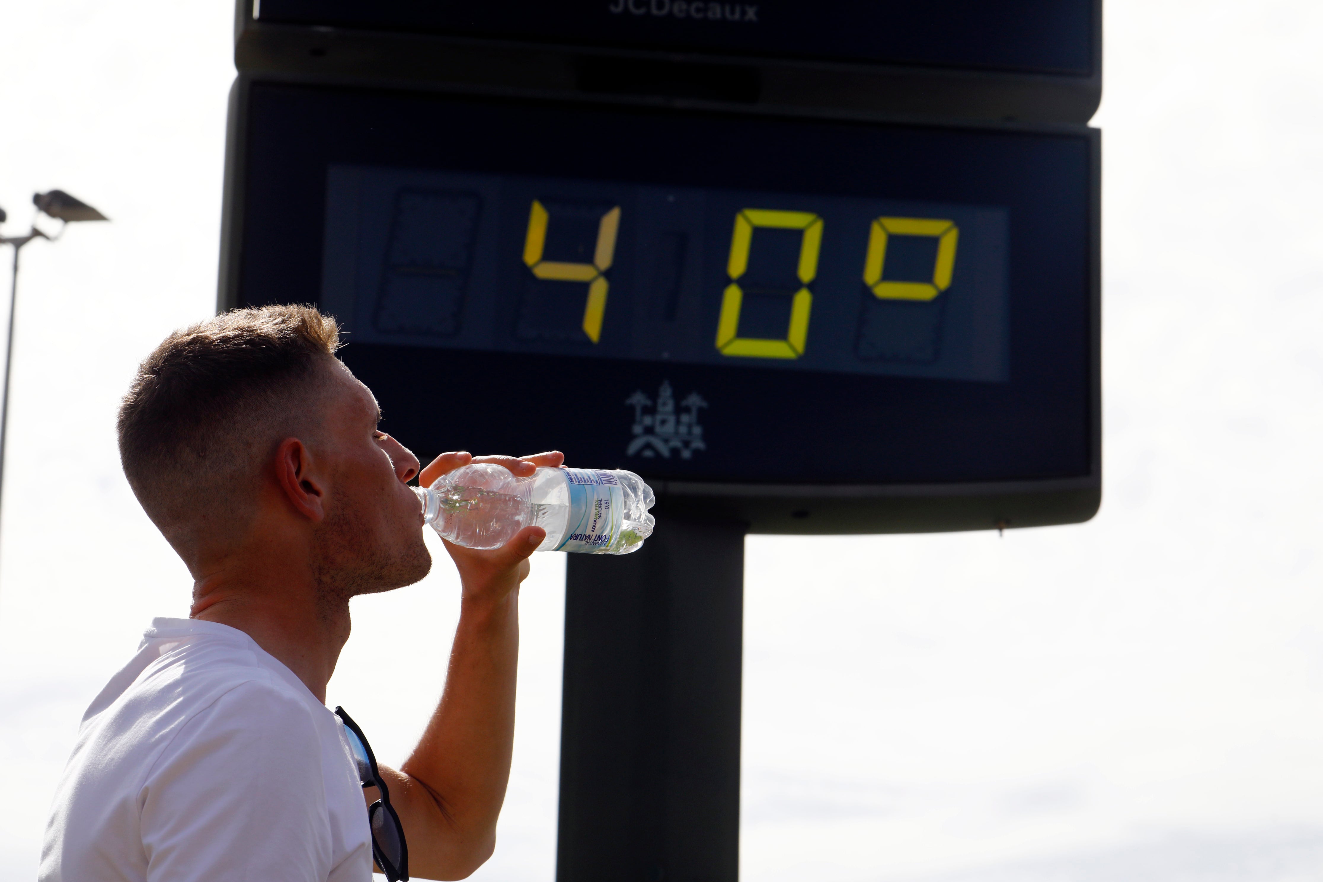 -FOTODELDÍA- CÓRDOBA, 27/04/2023.- Un joven bebe agua junto a un termómetro de calle que marca 40 grados en el centro de Córdoba a finales de abril. EFE / Salas