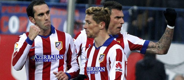 Los jugadores del Atlético de Madrid Fernando Torres, y el uruguayo Diego Godín celebran el gol marcado ante el Granada por su compañero, el croata Mario Mandzukic (d-atras), durante el partido de la decimonovena jornada de Liga de Primera División disput