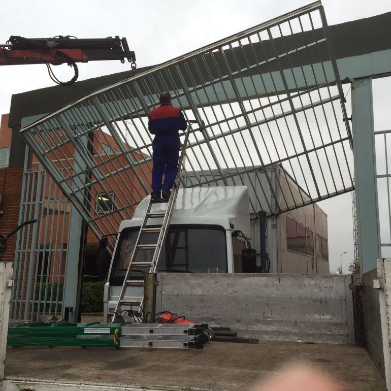 Operarios trabajan con una grúa en la retirada del portón en el que quedaba atrapado el vehículo.