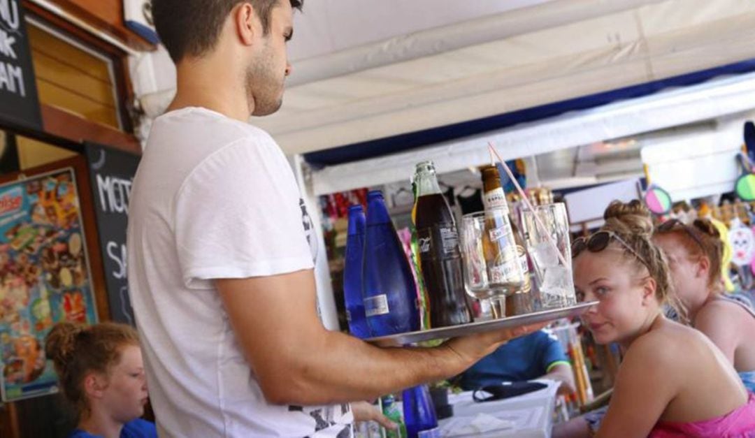 Un camarero atiende una mesa con turistas 