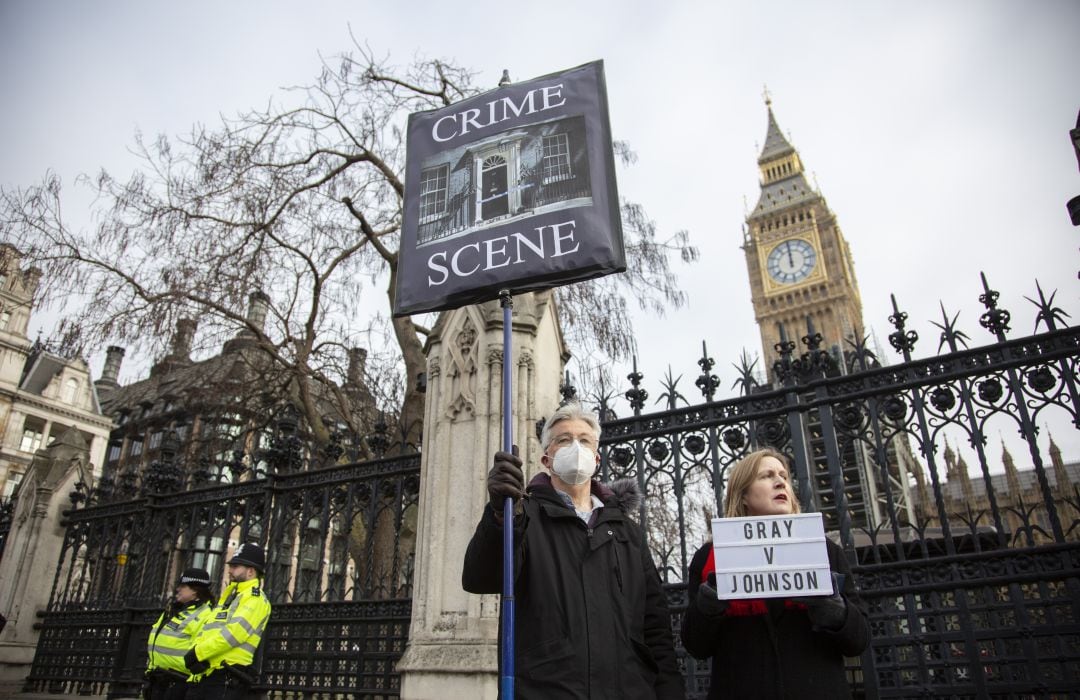 Ciudadanos protestando con un cartel que dice &#039;escena del crimen&#039;, acompañado de una foto de Downing Street, donde se celebraron las numerosas fiestas