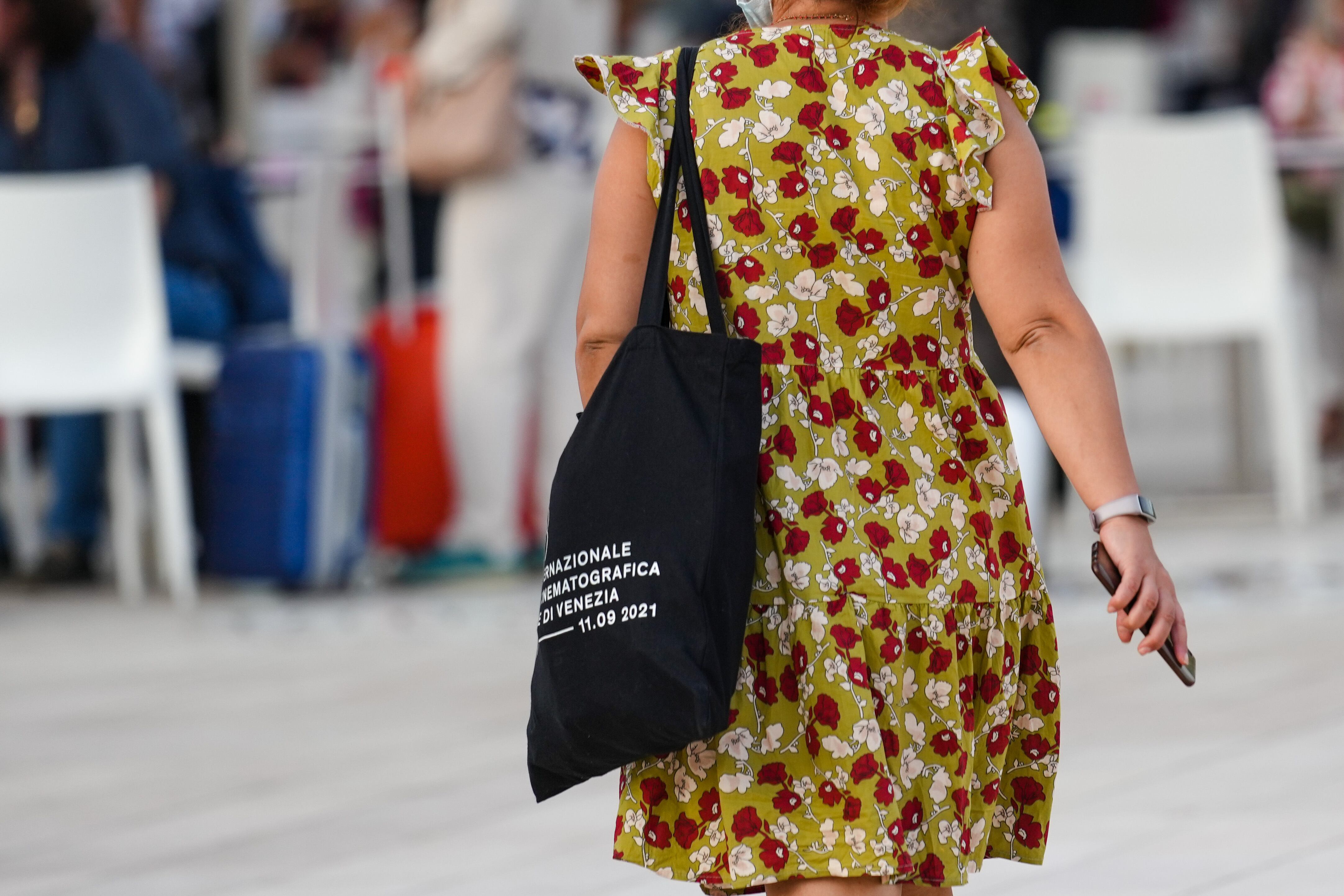 Una dona camina pel carrer amb una totebag del Festival de Venècia