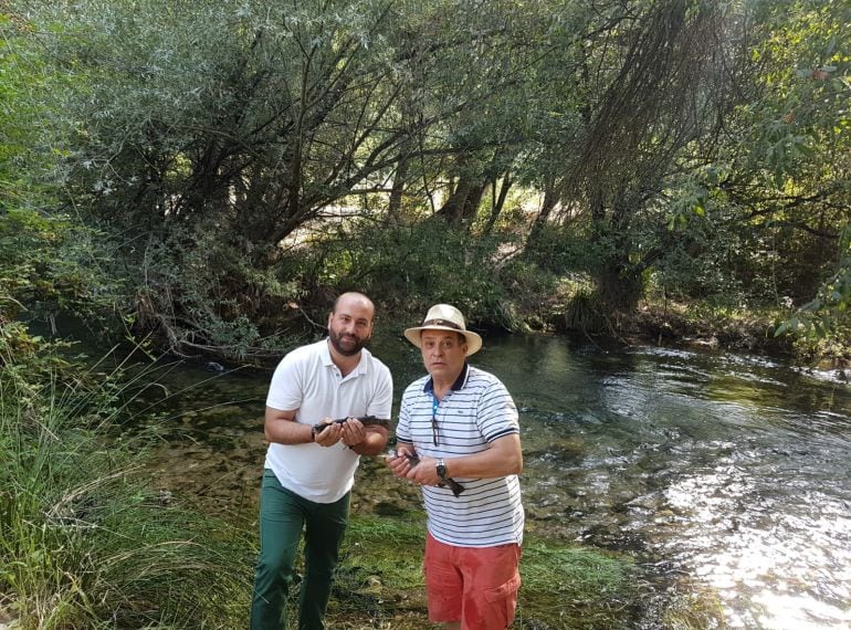 El alcalde de Pozo Alcón, Iván Cruz y el presidente del club de pesca, Antonio López con dos ejemplares de trucha arco iris a punto de echarlas al río