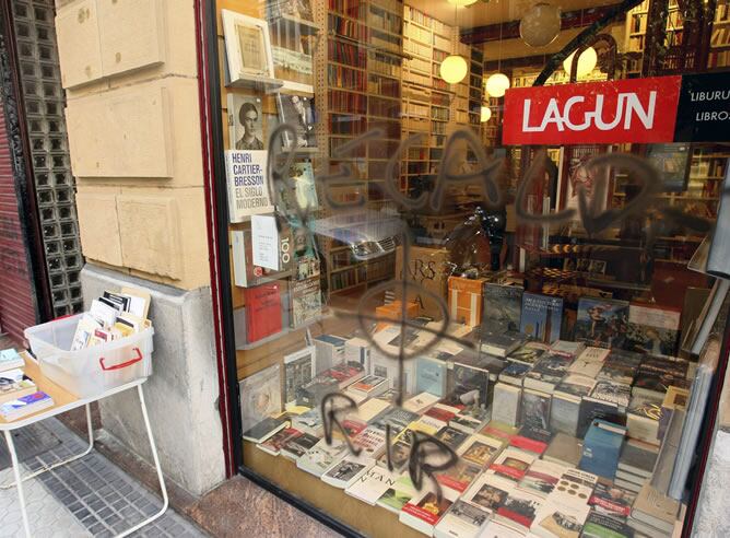 Cristal de la librería Lagun de San Sebastián, en el que ha aparecido hoy una pintada con amenazas de muerte contra el ex consejero vasco José Ramón Recalde, mientras que en la persiana de la puerta se observa el anagrama de ETA