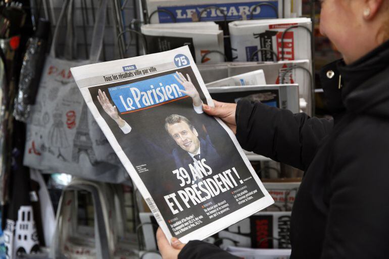 Una mujer mira la portada de &#039;Le Parisien&#039; con la foto de Macron como ganador de las presidenciales en Francia