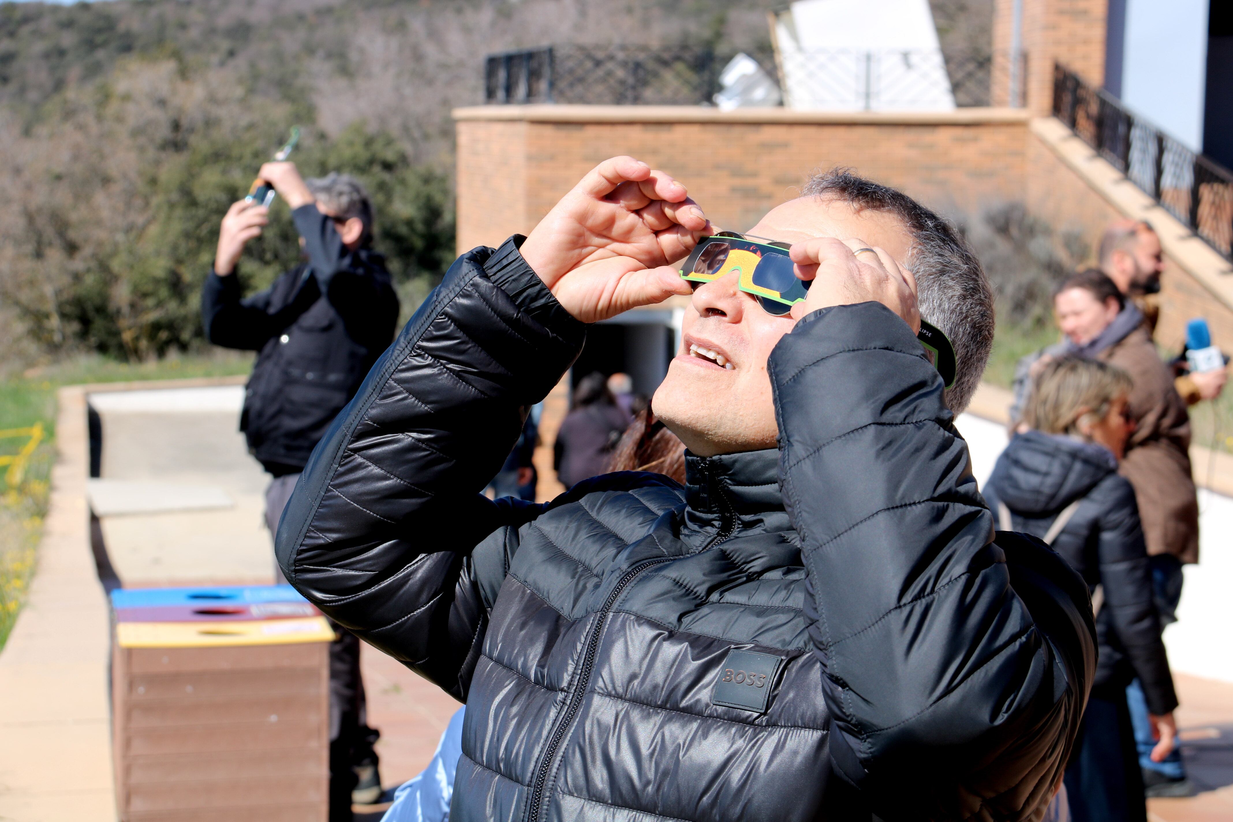 Un home observa un eclipsi solar amb les ulleres homologades.