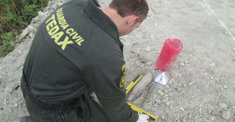 Un agente de la Guardia Civil mide el proyectil encontrado en Higuera de Calatrava.