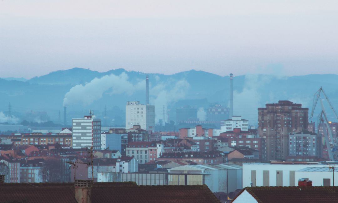 Gijón con las chimeneas de la industria al fondo. 