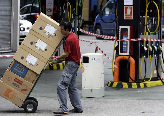 Un operario transporta algunas cajas ante una gasolinera sin servicio