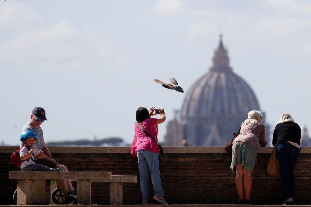 Personas con la cúpula de San Pedro en el fondo de la imagen