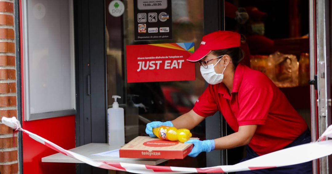 Una trabajadora de Telepizza protegida con una mascarilla y unos guantes de látex