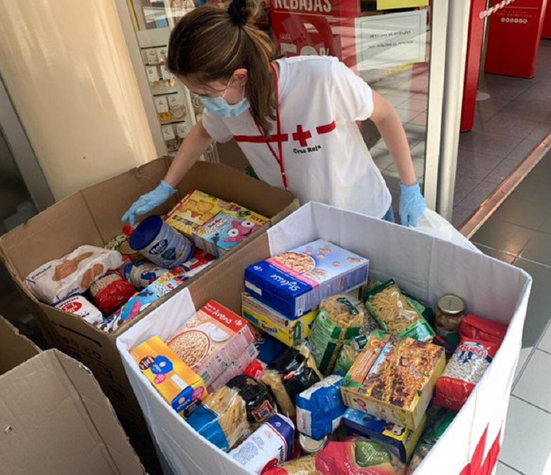 Una voluntaria de Cruz Roja colocando en uno de los contenedores  alimentos donados