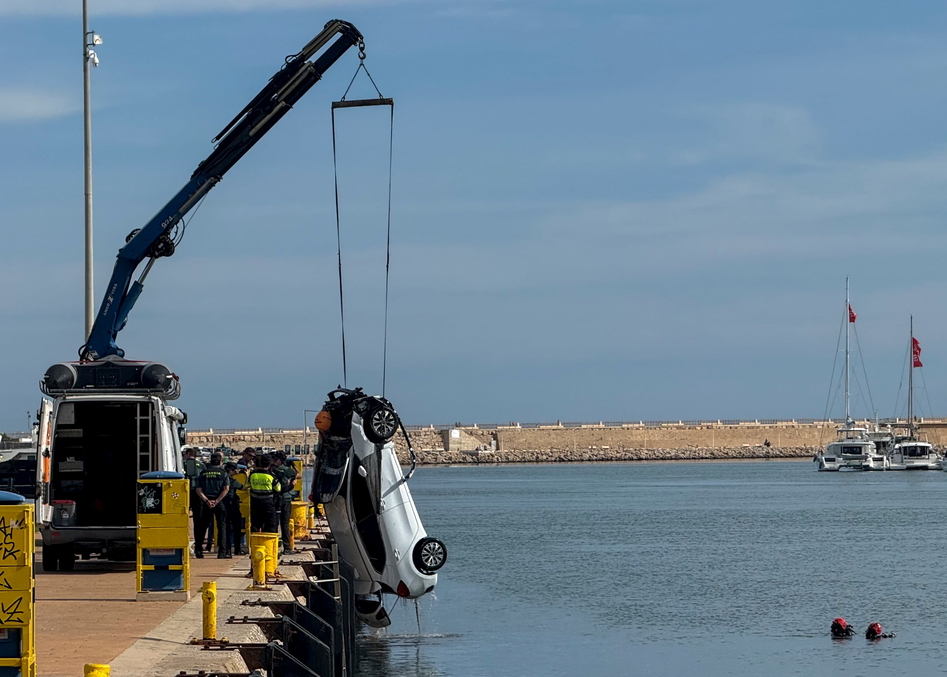 Una grúa saca el coche de la mujer que lo conducía en la noche del jueves cuando cayó al puerto de Gandia, accidente en el que murió una joven de 20 años. EFE/Raquel Segura