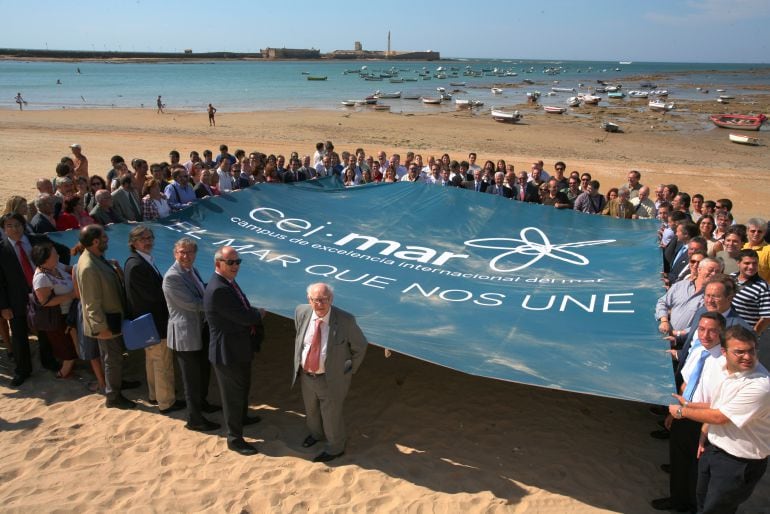 Autoridades sostienen sobre la playa de La Caleta una enorme pancarta del CEI.Mar