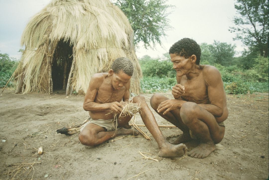 Un par de miembros de una tribu encienden un incendio fuera de una casa de césped tradicional en las colinas de Tsodilo, Botswana, 1985